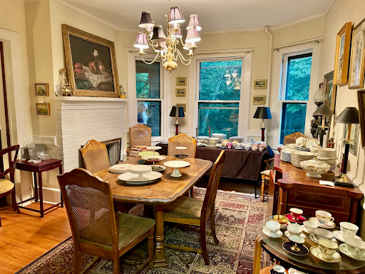 Vintage-style dining room with wooden furniture, chandelier lighting, and a table set with elegant dishware and teacups