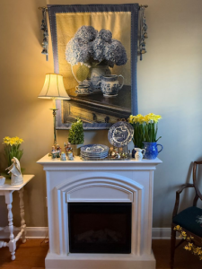 Vintage home décor display with framed artwork, lamp, and decorative plates staged for an estate sale